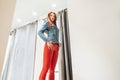 Slim girl with redheads chooses clothes. woman in red leather pants posing in fitting rooms. bottom view
