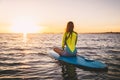 Slim girl on stand up paddle board on a quiet sea with summer sunset colors. Relaxing in ocean Royalty Free Stock Photo