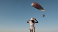Slim girl stands and looks at the paraglider. Woman stands on a hill holding a hat in her hands and looks at a