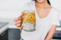 The slim girl young woman holding glass jar with lemon water in kitchen, close up Royalty Free Stock Photo