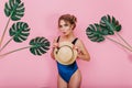 Slim graceful curly girl with lovely face expression posing, holding vintage hat isolated on pink wall. Adorable young