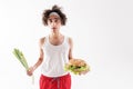 Slim guy choosing between healthy and unhealthy food