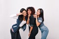 Slim latin girl in white tank-top standing with peace sign beside black and asian ladies on white background. Brunette Royalty Free Stock Photo