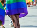 Slim legs of a young woman from behind with fishnet stockings with woven skulls and a cape in the colors of the rainbow Royalty Free Stock Photo