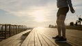 Sportsman is squatting in sunny evening on city embankment, detail view of body