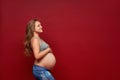 Slim, pregnant girl in sportswear, embracing belly smiling looking aside