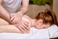 Side View on unrecognizable redhead woman enjoying massage on back and shoulders lying on belly. Royalty Free Stock Photo