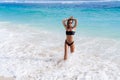 Slim sexy girl in black swimsuit and sunglasses posing on ocean beach