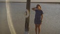 Slim girl enjoying sunset, stands near a wooden salt pillar of a salt lake