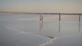 Slim girl enjoying sunset, walks between wooden salt pillars of a salt lake