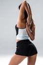 Slim and sport young woman posing and doing sport exercises standing with her back to the camera and stretching arms in Royalty Free Stock Photo