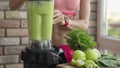 Slim sporty woman making a homemade green detox smoothie