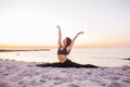 Slim strong young woman in black practicing yoga doing the splits on sand beach close-up with copy space. Sunset, summer. Healhy