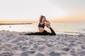 Slim strong young woman in black practicing yoga doing the splits on sand beach close-up with copy space. Sunset, summer. Healhy Royalty Free Stock Photo