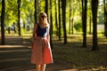 Slim tall girl with blond hair wearing sunglasses in a blue top and a light skirt walks in the Park. horizontal photography