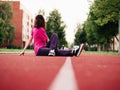 Slim teenager girl doing stretching on a red running line. Selective focus. Sport and fitness concept. Young athlete in red t Royalty Free Stock Photo