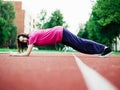 Slim teenager girl doing stretching on a red running line. Selective focus. Sport and fitness concept. Young athlete in red t Royalty Free Stock Photo