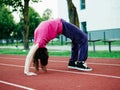 Slim teenager girl doing stretching on a red running line. Selective focus. Sport and fitness concept. Young athlete in red t Royalty Free Stock Photo