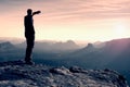 Slim tourist on the sharp peak of rock in rock empires park is watching over the misty and foggy valley to Sun