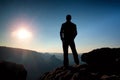 Slim tourist on sharp peak of rocky mountain is watching over misty and foggy morning valley to Sun Royalty Free Stock Photo