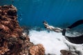 Slim woman in bikini swim with fins near coral reef in blue ocean. Freediving with sexy girl