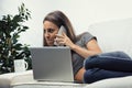 Slim woman on couch with laptop, sly smile and phone with amusin Royalty Free Stock Photo