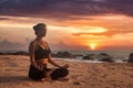 Slim woman does yoga in lotus posture on tropical sea coast or ocean beach outdoors on sunset Royalty Free Stock Photo