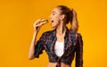 Slim Woman Eating Burger Having Cheat Meal Day, Yellow Background