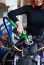 Redhead female driver fueling own bike in service