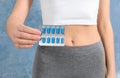 Slim woman holding weight loss pills in blister pack against color background Royalty Free Stock Photo