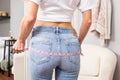 Slim woman in jeans measuring her bottom with a measure tape