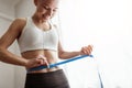 Slim woman measuring waist with tape