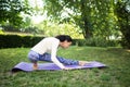 A slim woman in the park making beautiful asana exercises. Sporty woman practicing yoga in the summer park. Yoga, fitness, sport. Royalty Free Stock Photo