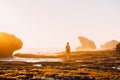 Slim woman posing near ocean with rocks and sunset colors. Woman traveller in ocean Royalty Free Stock Photo