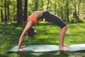 Athletic lady is standing in gymnastic bridge in nature