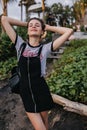 Slim woman in vintage casual attire posing with eyes closed. Outdoor portrait of graceful young lady in trendy t-shirt