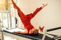 Slim woman wearing sports attire having anaerobic exercise on reformer