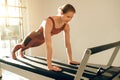 Slim woman wearing sports attire having anaerobic exercise on reformer