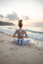 Slim yogi woman sitting in Padmasana  Lotus Pose on the beach. Hands in namaste mudra. View from back. Self care concept. Yoga Royalty Free Stock Photo