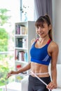 Slim young asian woman measuring herself with measureing tape at home Royalty Free Stock Photo