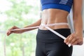 Slim young asian woman measuring herself with measuring tape at home Royalty Free Stock Photo