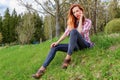 Young awesome woman sitting on the grass on the slope