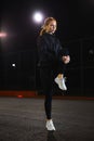 Slender young woman doing stretching workout outdoors in city street at night. Royalty Free Stock Photo