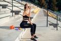 Young caucasian woman drinks water and listen to music after training.