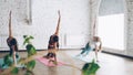 Slim young ladies are doing side plank pose Vasisthasana while practicing yoga in modern studio. Gracious women and