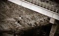 Slim young man standing under bridge of the urban riverbank Royalty Free Stock Photo