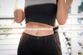 Slim young sport girl measuring her thin waist with tape measure, her exercise partner trainer helping her to measure her waist, Royalty Free Stock Photo