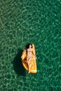 Slim young woman in bikini and sunglasses on the air mattress floats in the open sea