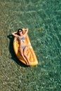 Slim young woman in bikini and sunglasses on the air mattress floats in the open sea Royalty Free Stock Photo