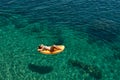 Slim young woman in bikini and sunglasses on the air mattress floats in the open sea